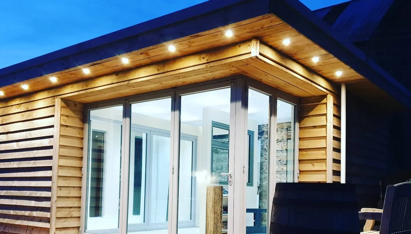 Aluminium bi-fold doors on the showroom exterior lit at dusk