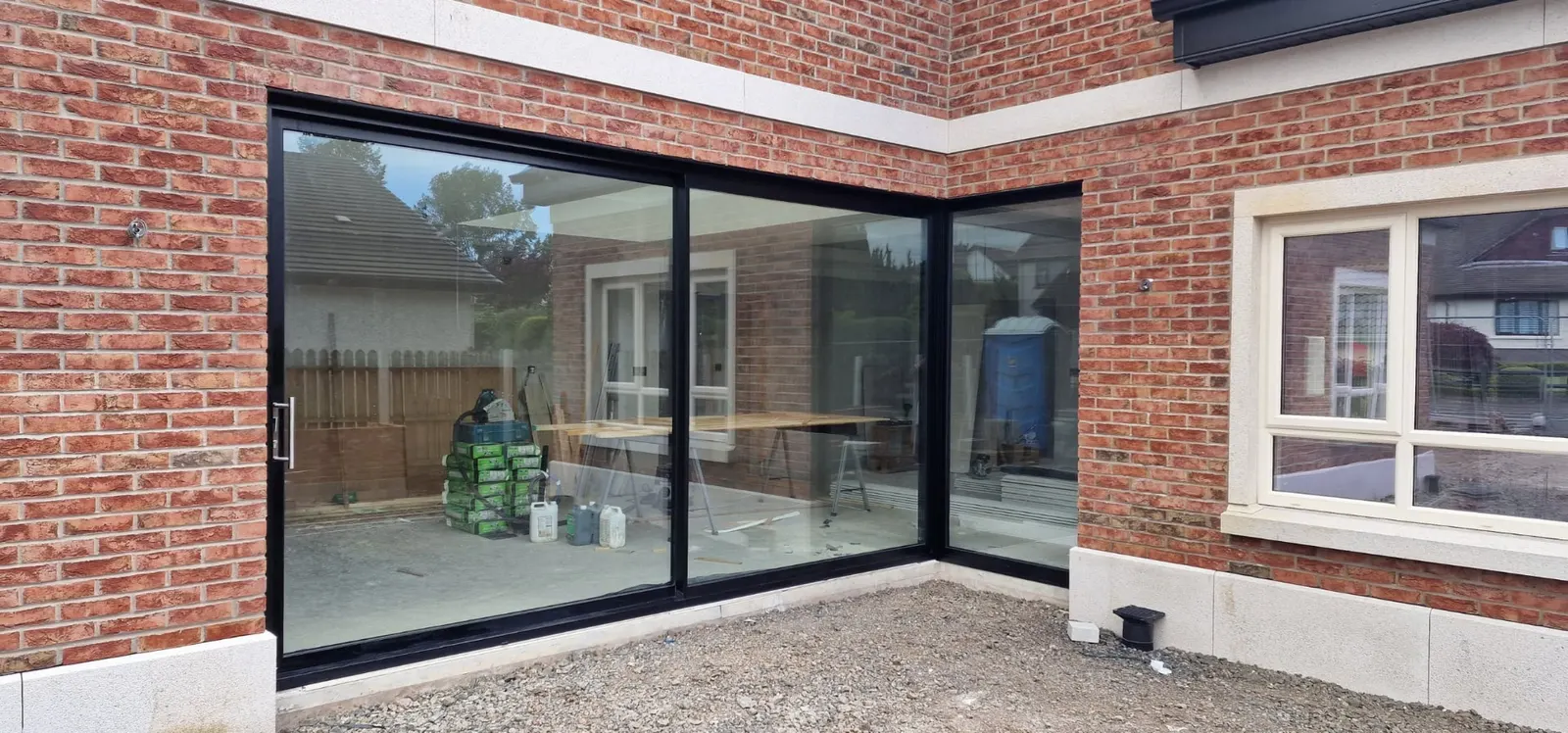 Aluminium corner sliding doors opening two sides of a brick house