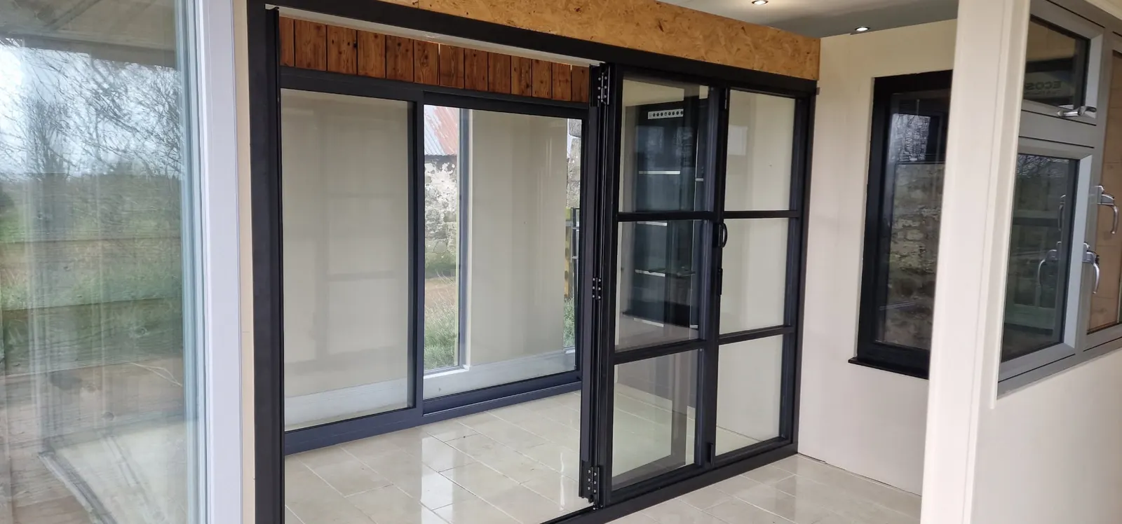 Black aluminium sliding and bi-fold doors displayed side by side in the showroom