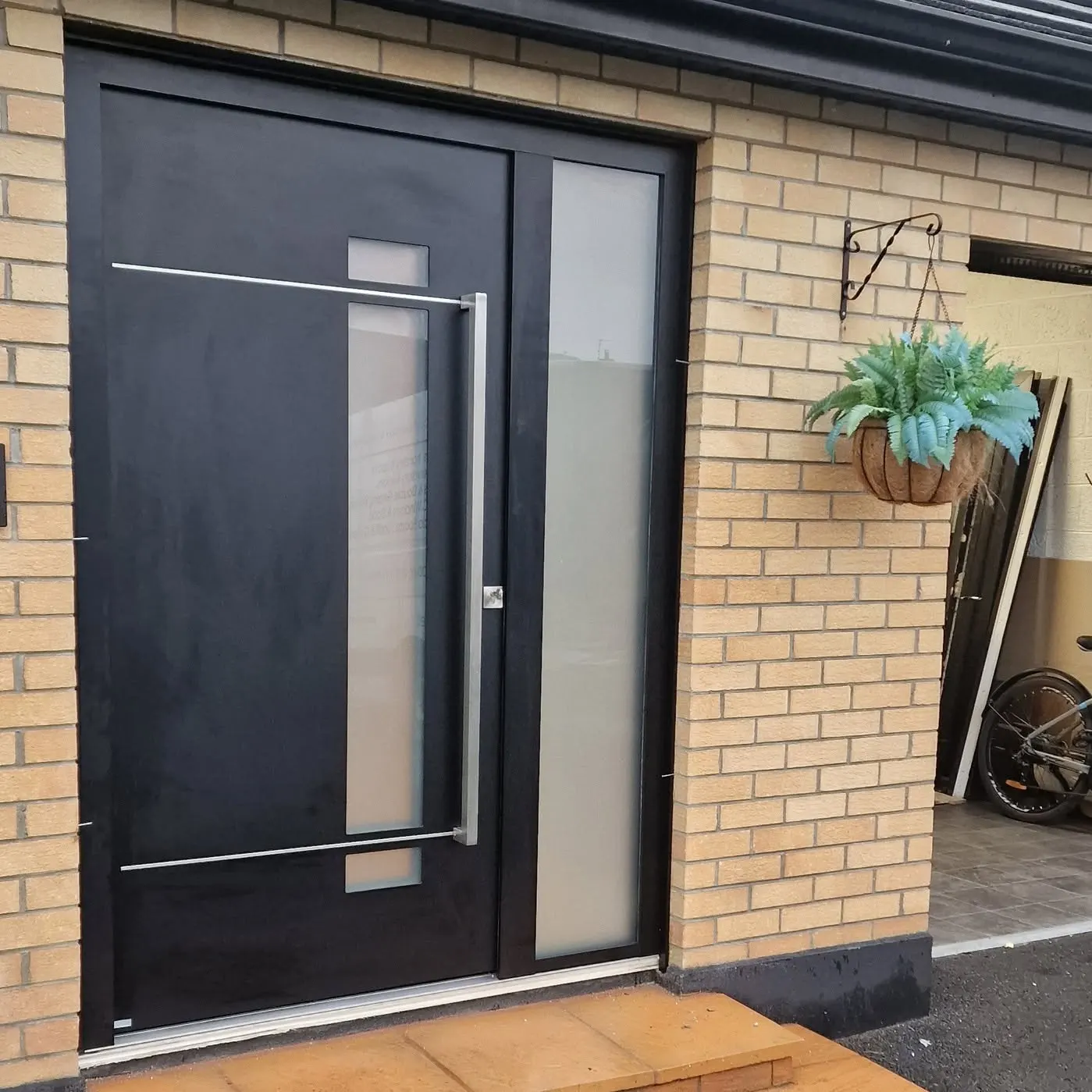 Black Origin aluminium front door with stainless bar handle and frosted side panel, Northern Ireland
