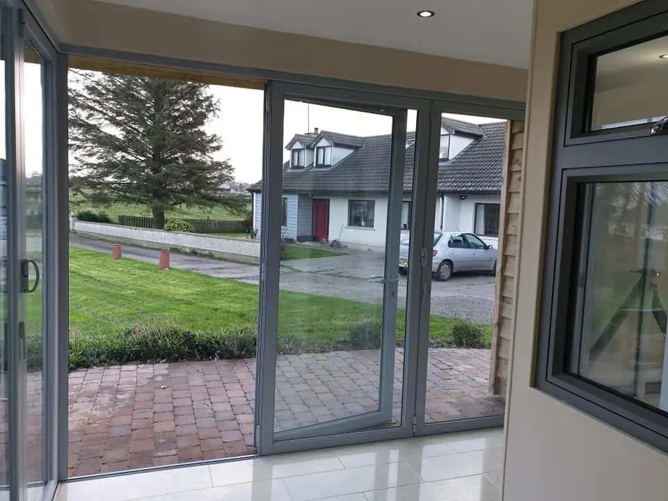Grey aluminium bi-fold doors seen from inside, looking onto a garden