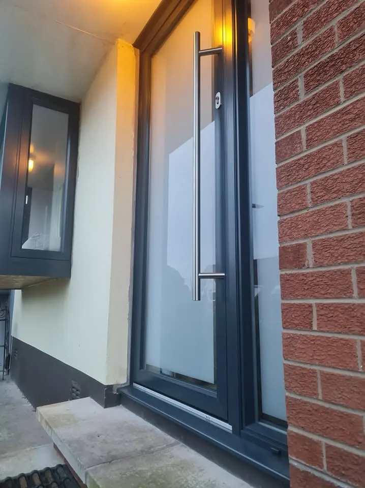 Grey aluminium front door with full-height frosted glass and long pull handle