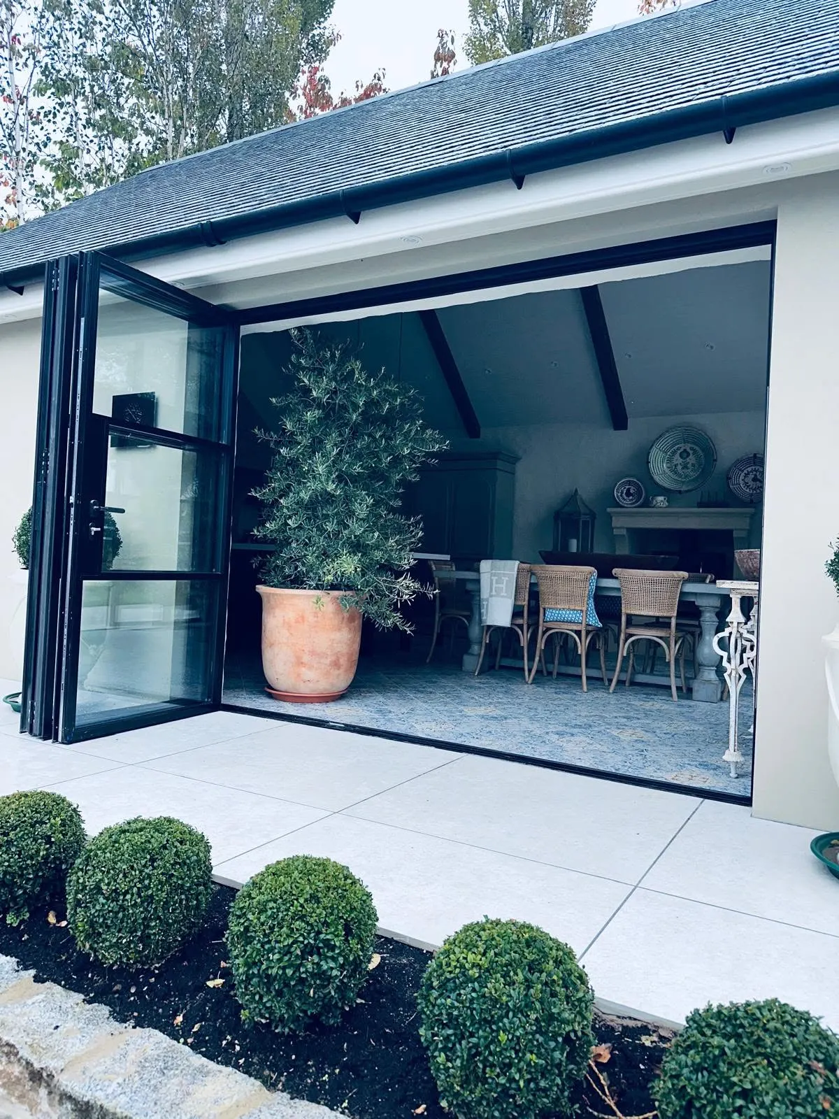 Black steel-look aluminium bi-fold doors folded open onto a patio