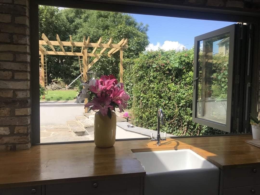 Aluminium bi-fold window open over a kitchen sink onto the garden, Northern Ireland