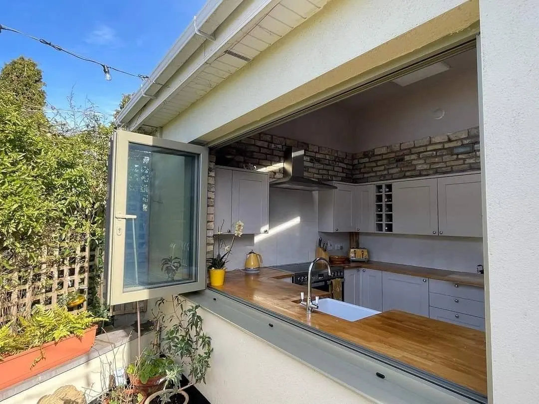 Aluminium bi-fold kitchen window folded open onto a patio