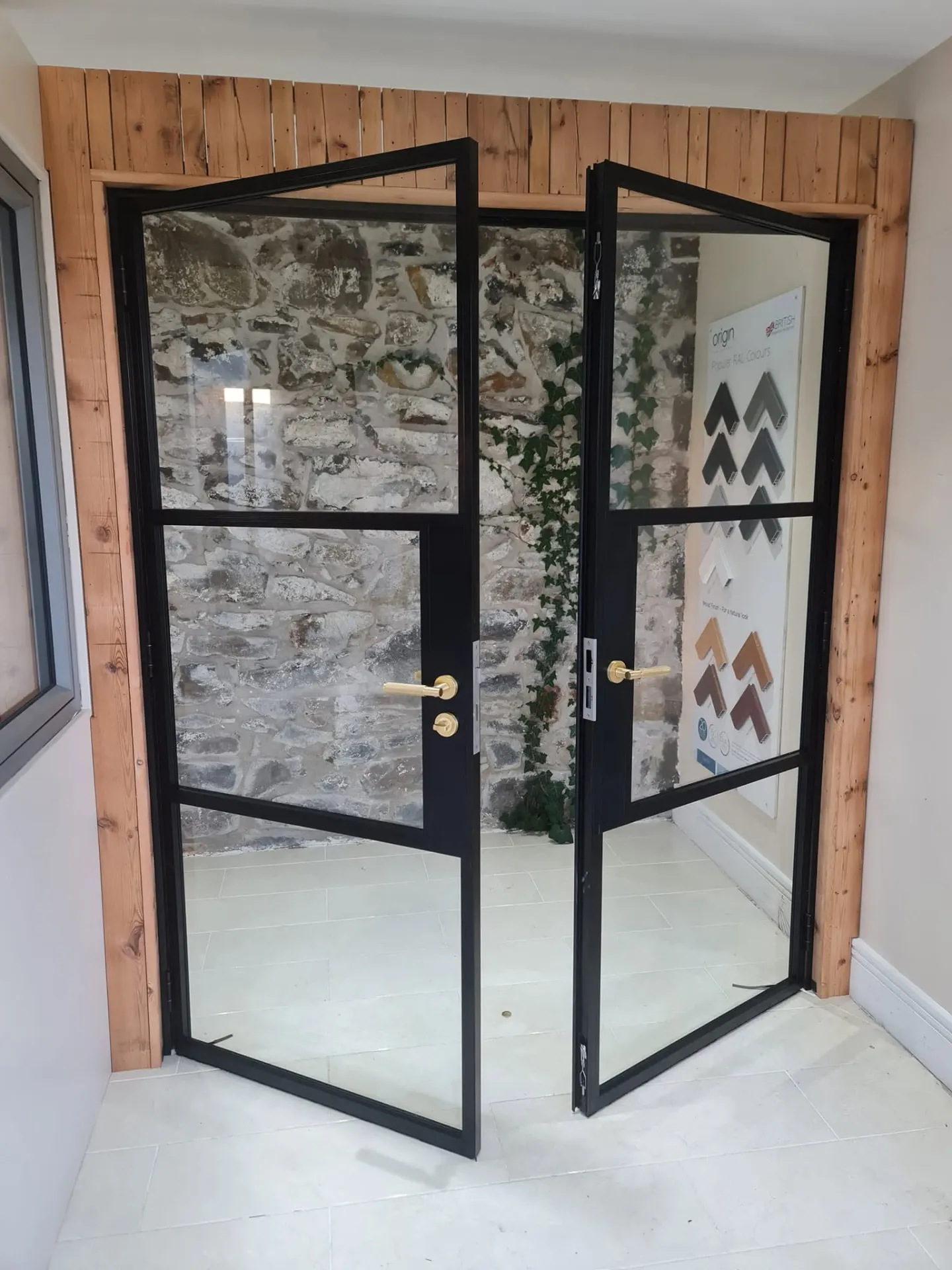 Black steel-look glazed double doors with brass handles in the Coleraine showroom