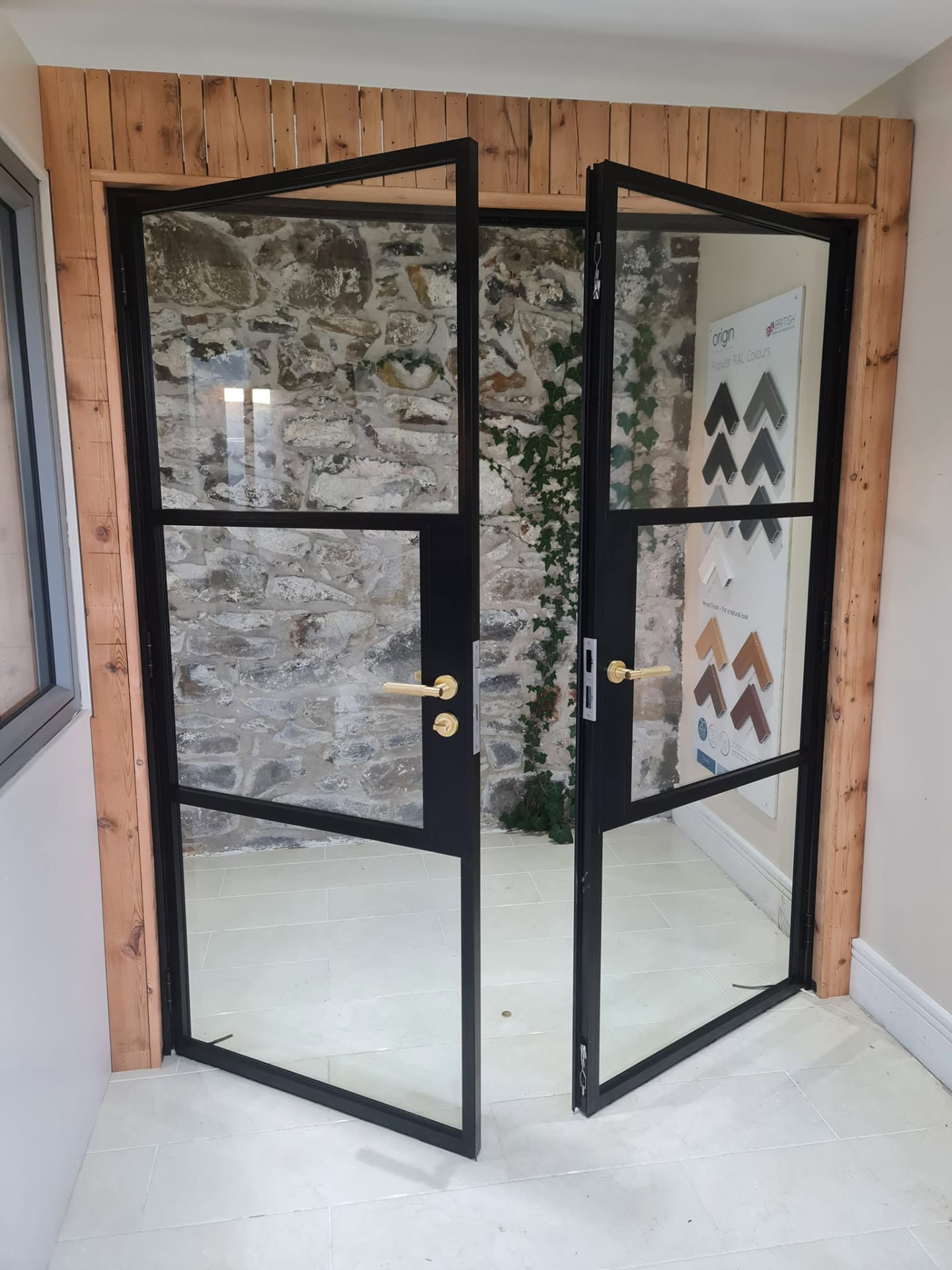 Black steel-look glazed double doors with brass handles in the Coleraine showroom
