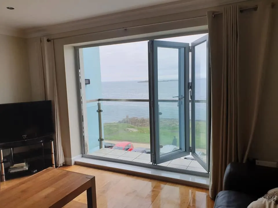 Grey aluminium French doors opening onto a balcony with a sea view
