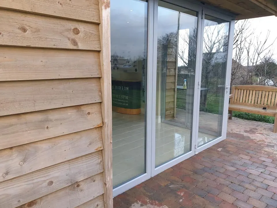 White aluminium bi-fold doors fitted in the timber-clad showroom