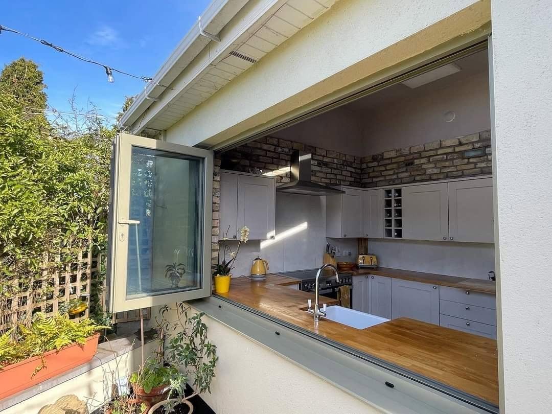 Aluminium bi-fold kitchen window folded open onto a patio