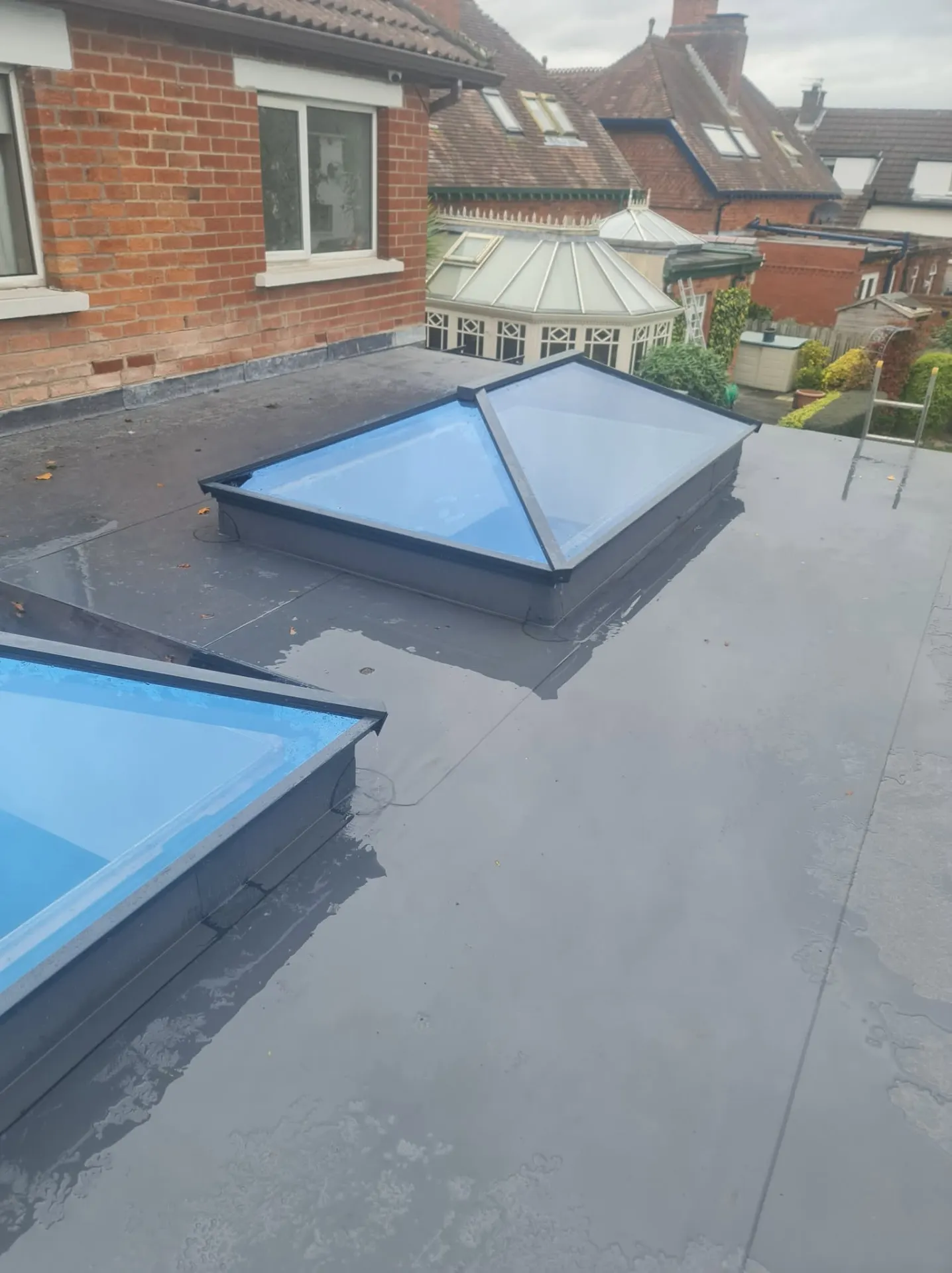 Roof lantern on a flat roof beside a red brick house