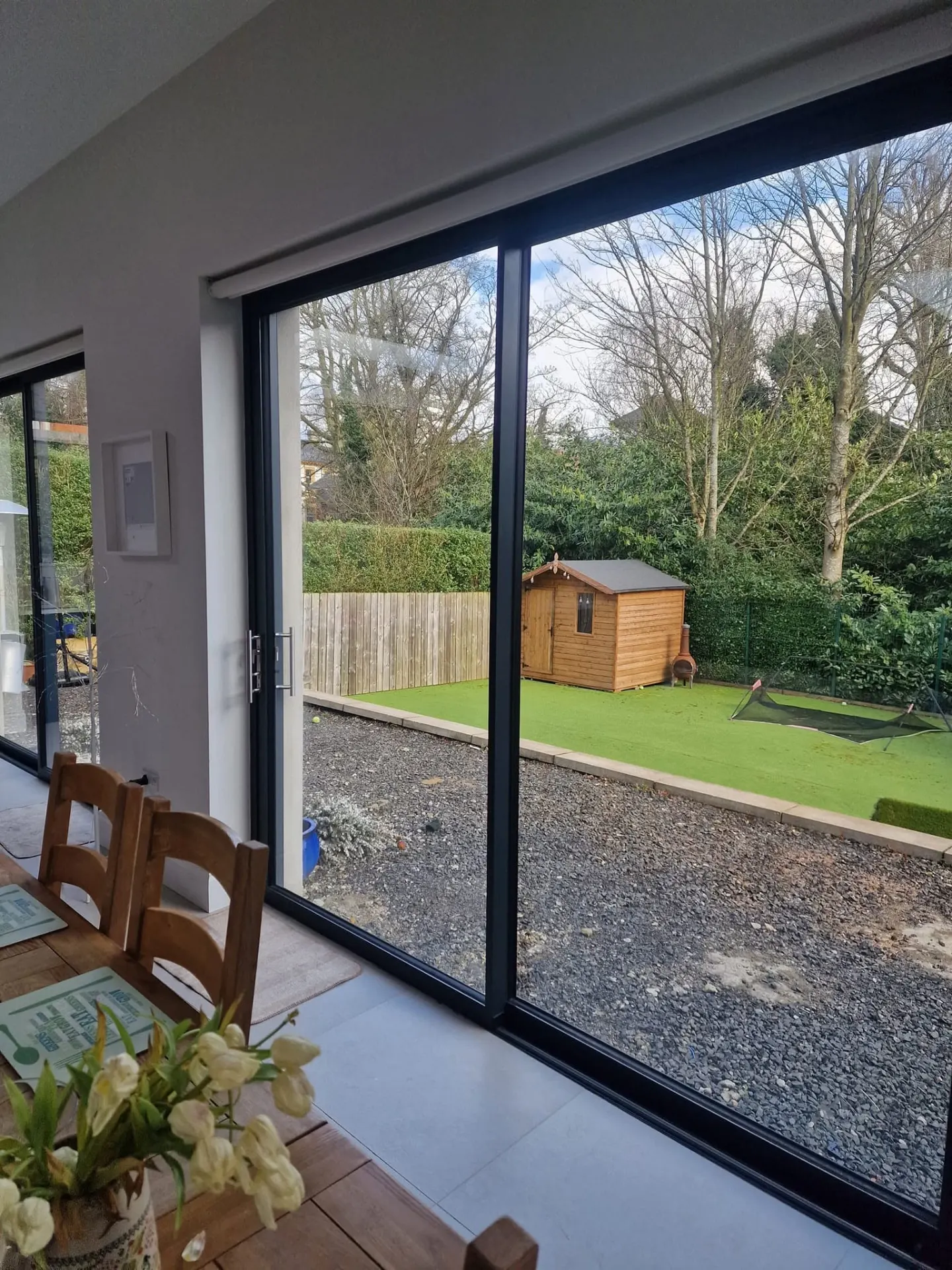 Slim aluminium sliding doors from inside, looking onto a lawn